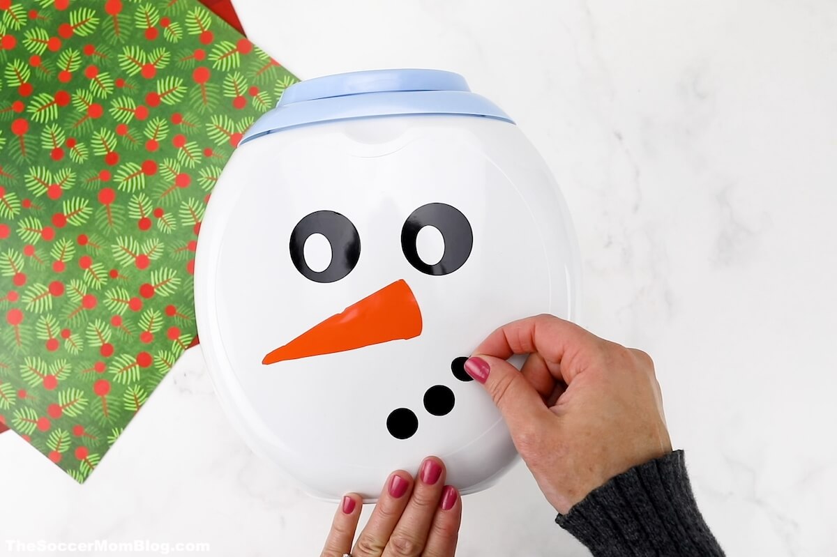 making a snowman face on the front of a white laundry pod container