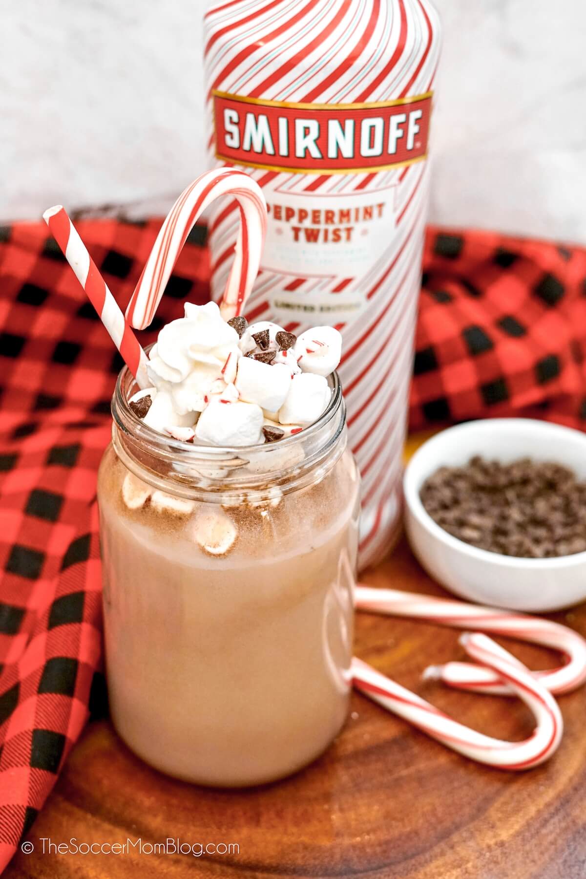 boozy hot chocolate with peppermint vodka bottle behind it
