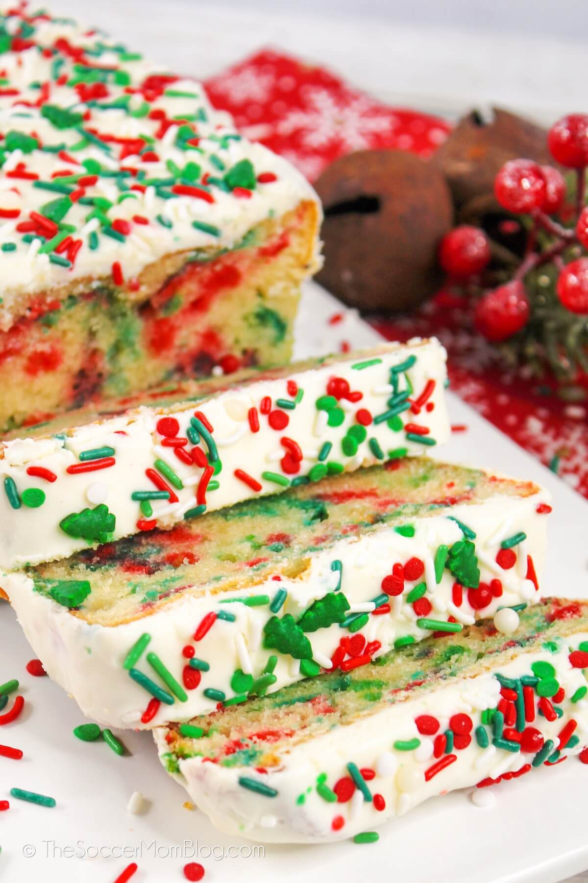 An iced Christmas loaf cake sliced to reveal red and green sprinkles inside