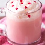 clear mug with pink hot chocolate and heart sprinkles
