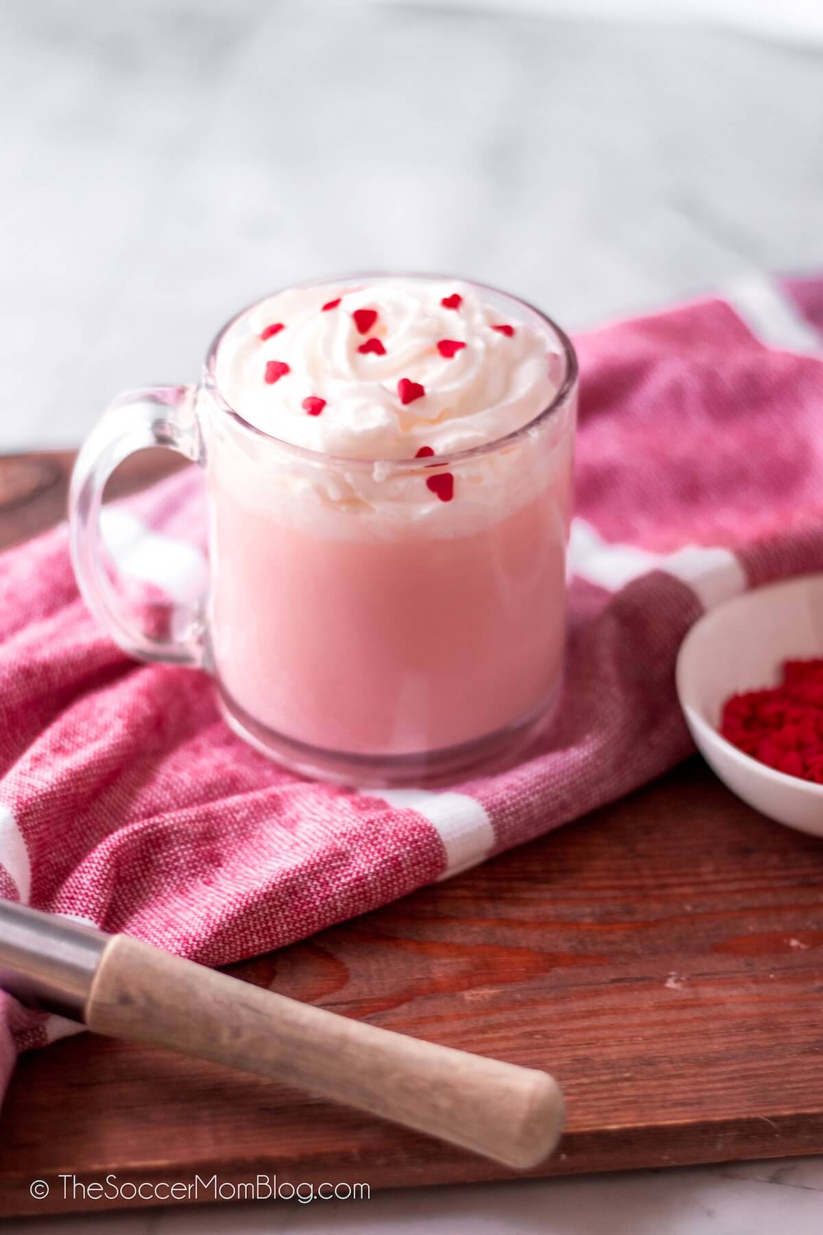 pink hot chocolate for Valentine's Day, with whisk and heart sprinkles
