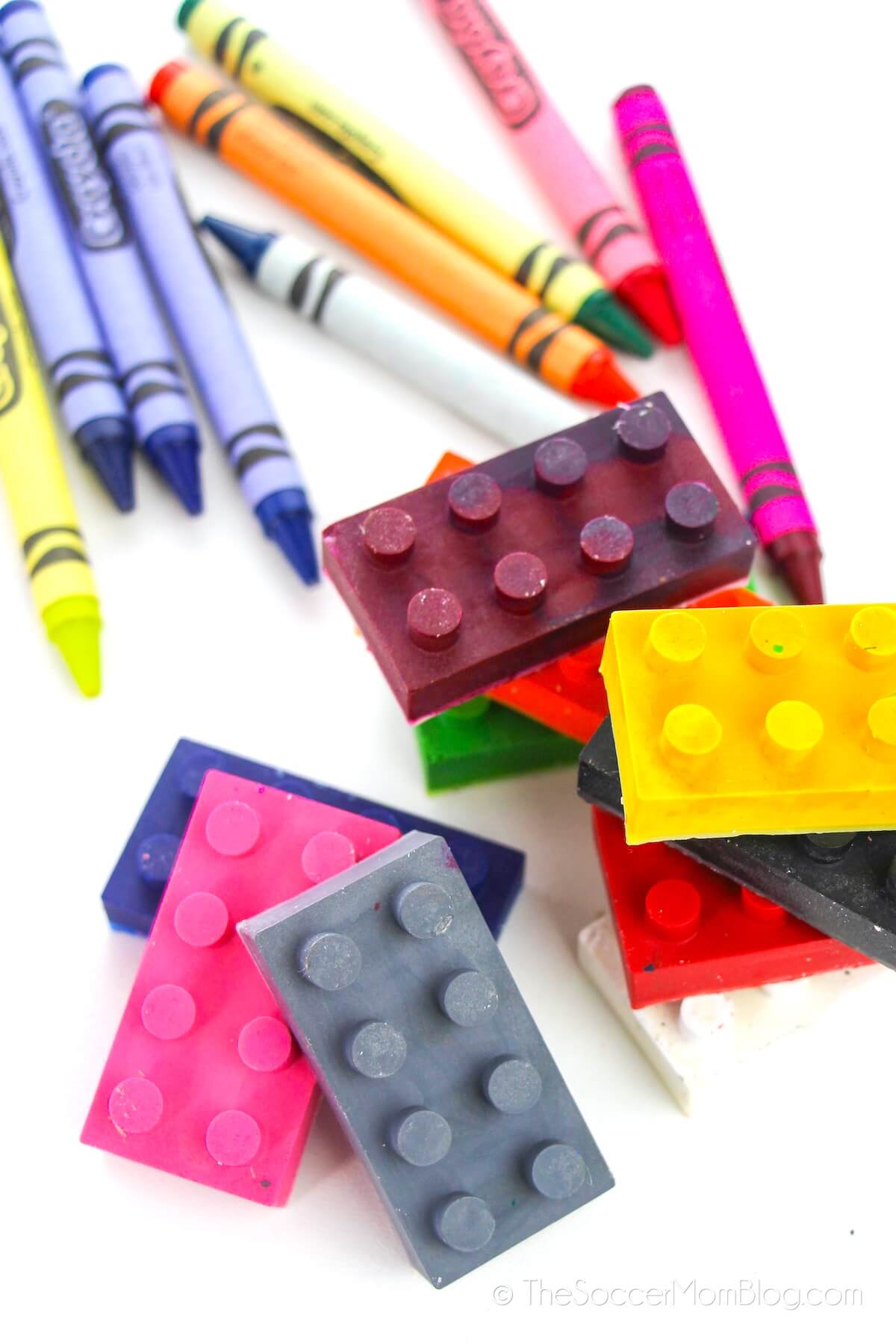 Homemade LEGO crayons, with regular crayons behind them on a white background