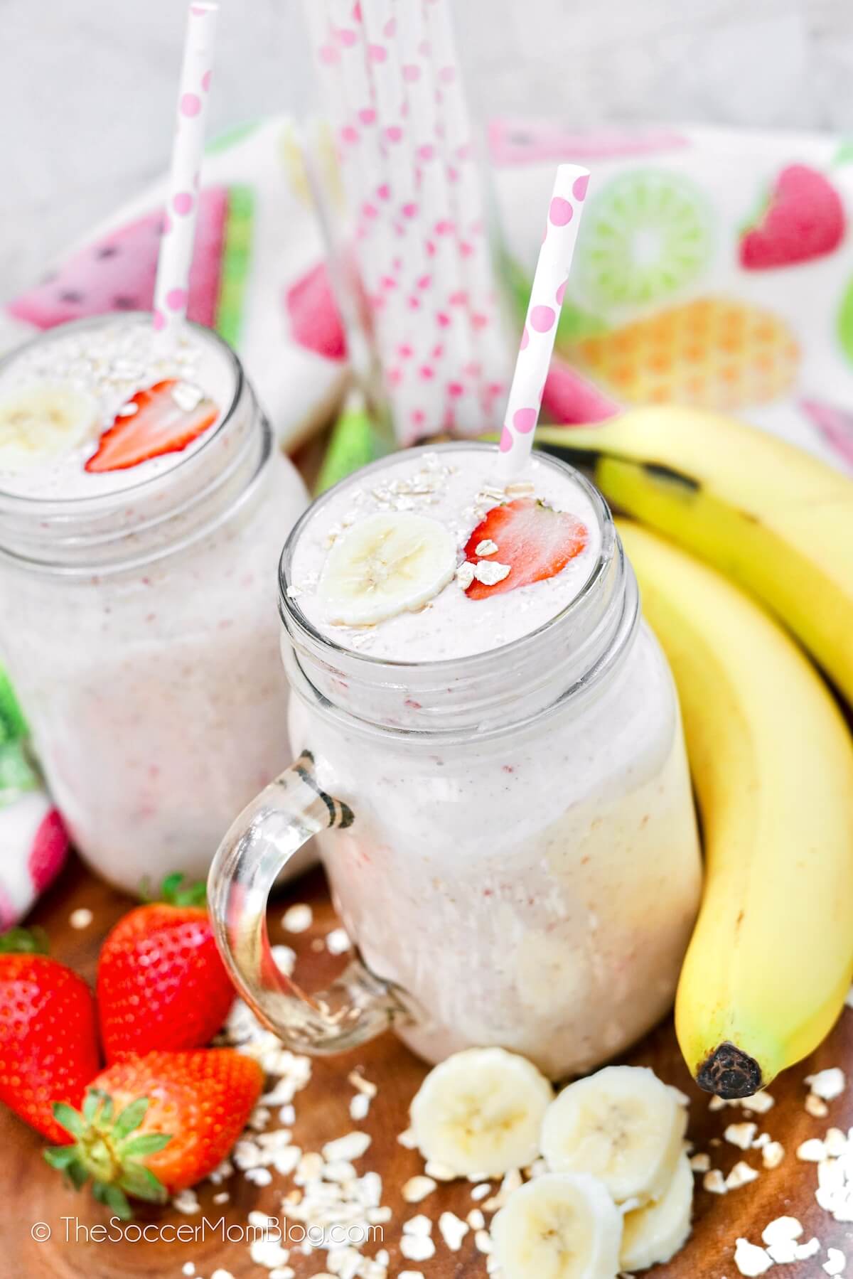 Two Strawberry Banana Smoothies, in mason jars, Surrounded by fruit