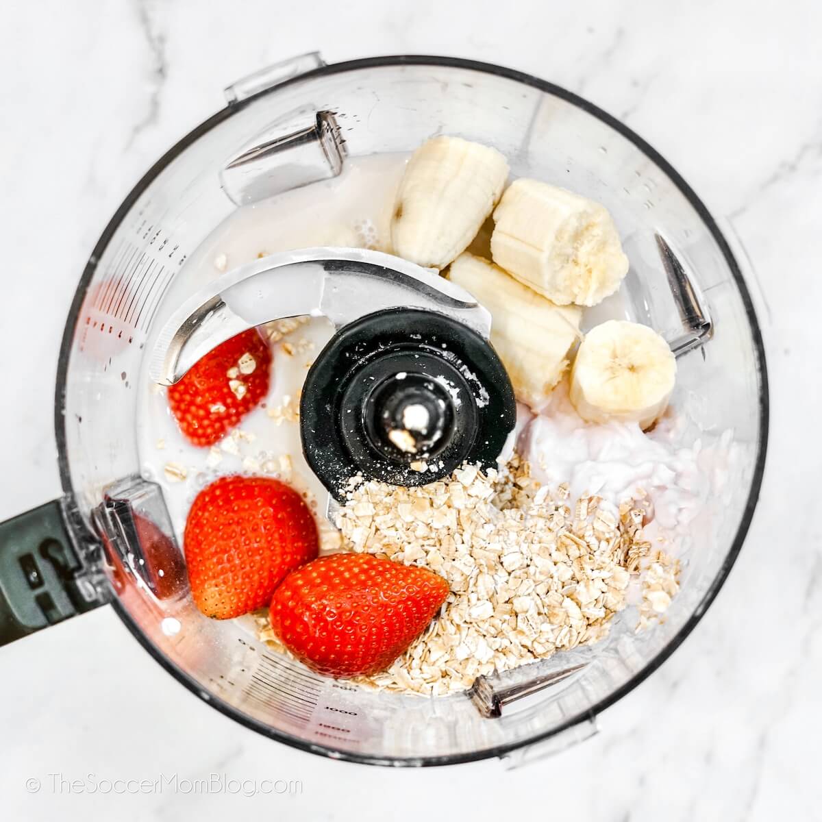 Top-down view of Strawberries, Bananas, and rolled oats in a blender