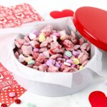 Valentine tin filled with red and pink candy coated Chex mix blended with conversation hearts