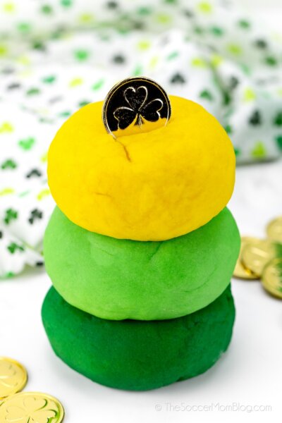 stack of dark green, light green, and yellow balls of playdough with gold coin on top, for St. Patrick's Day
