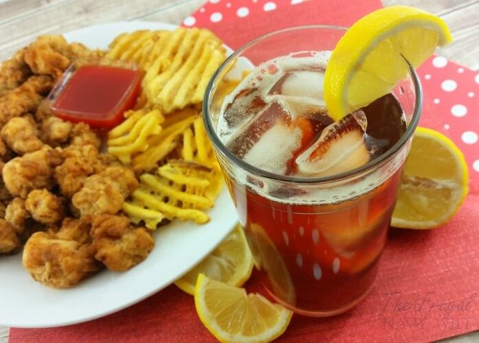 glass of sweet tea and a plate of chicken nuggets and waffle fries