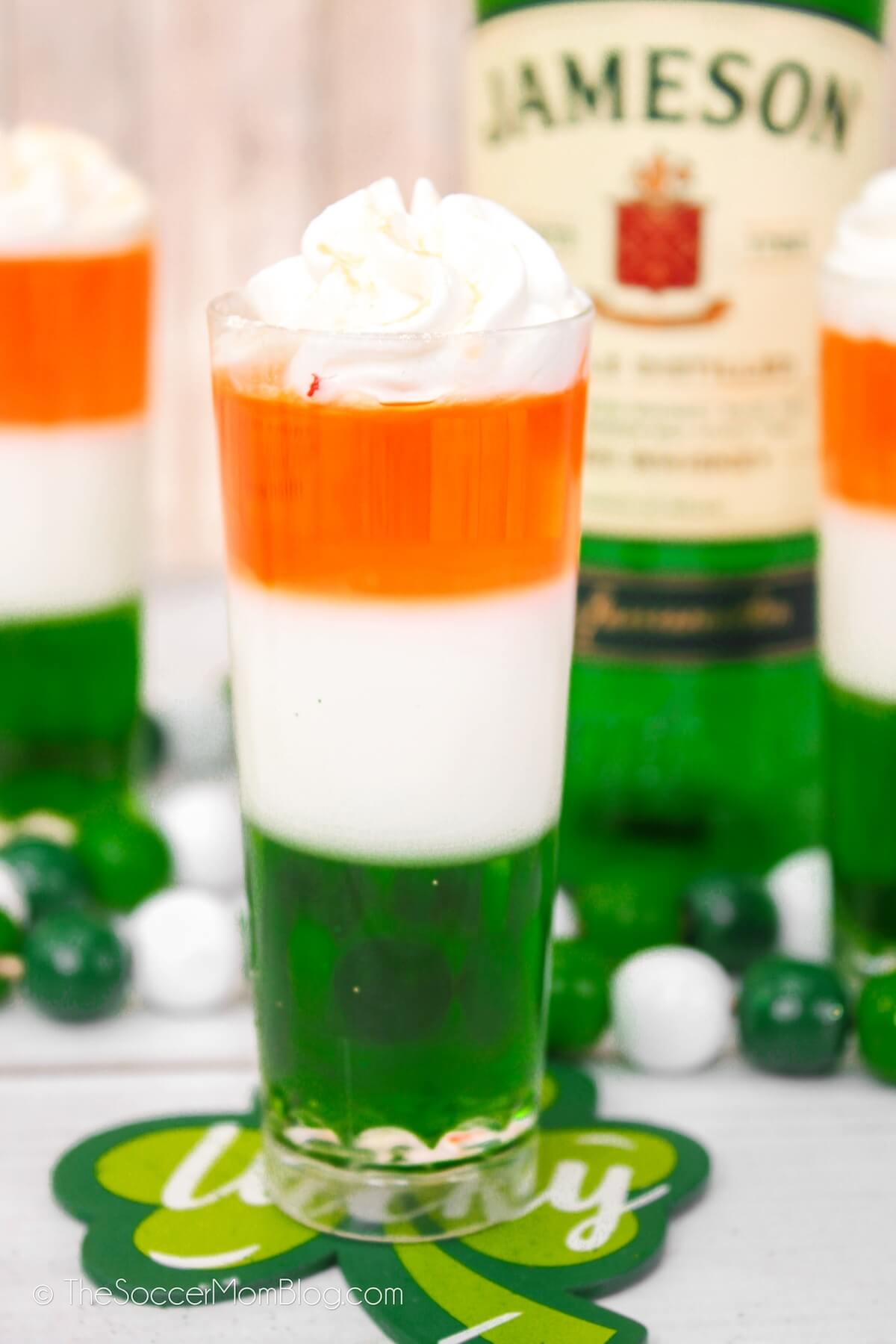 layered St. Patrick's Day jello shots in the colors of the Irish flag, with Jameson bottle in background