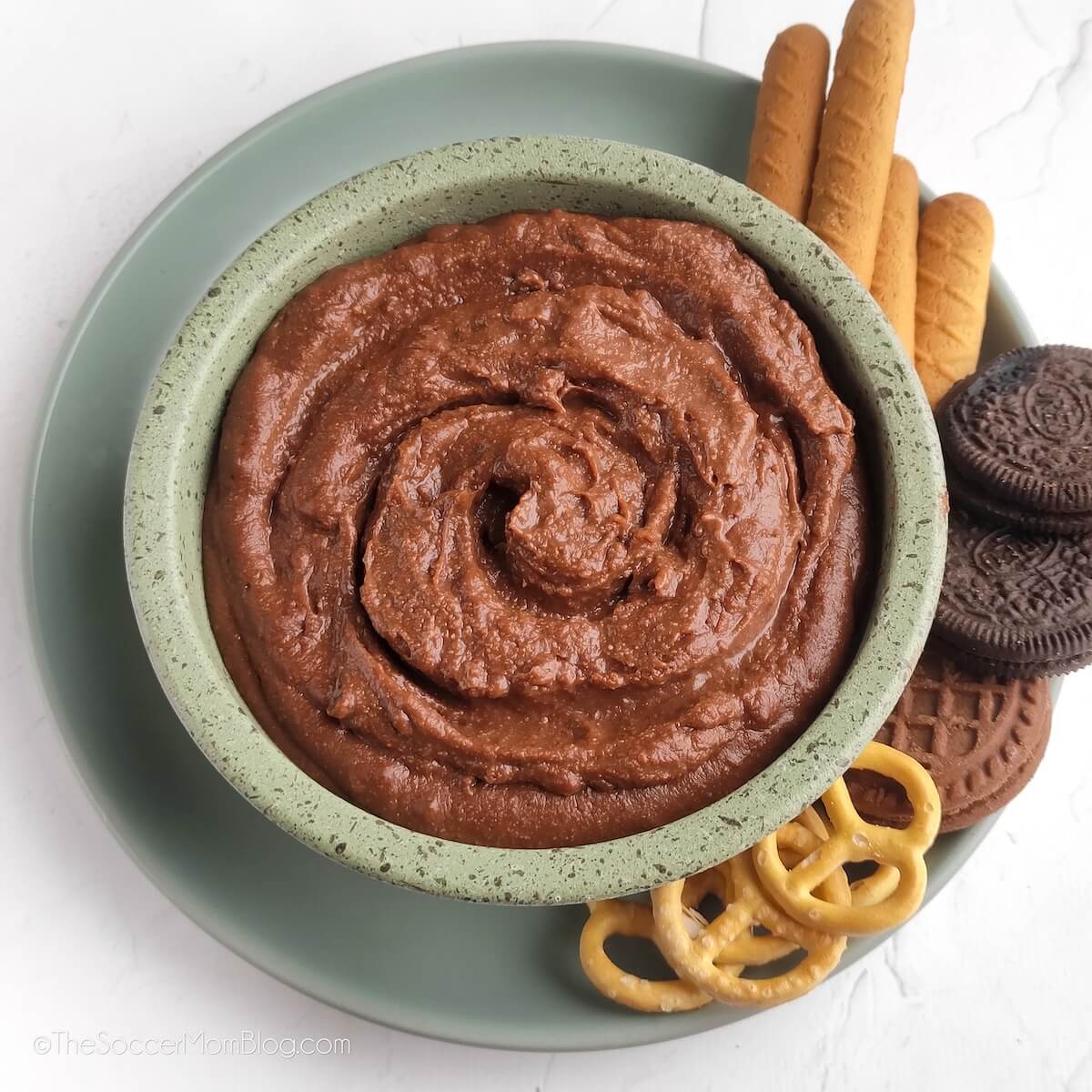 small bowl of chocolate hummus, with cookies and pretzels for dipping