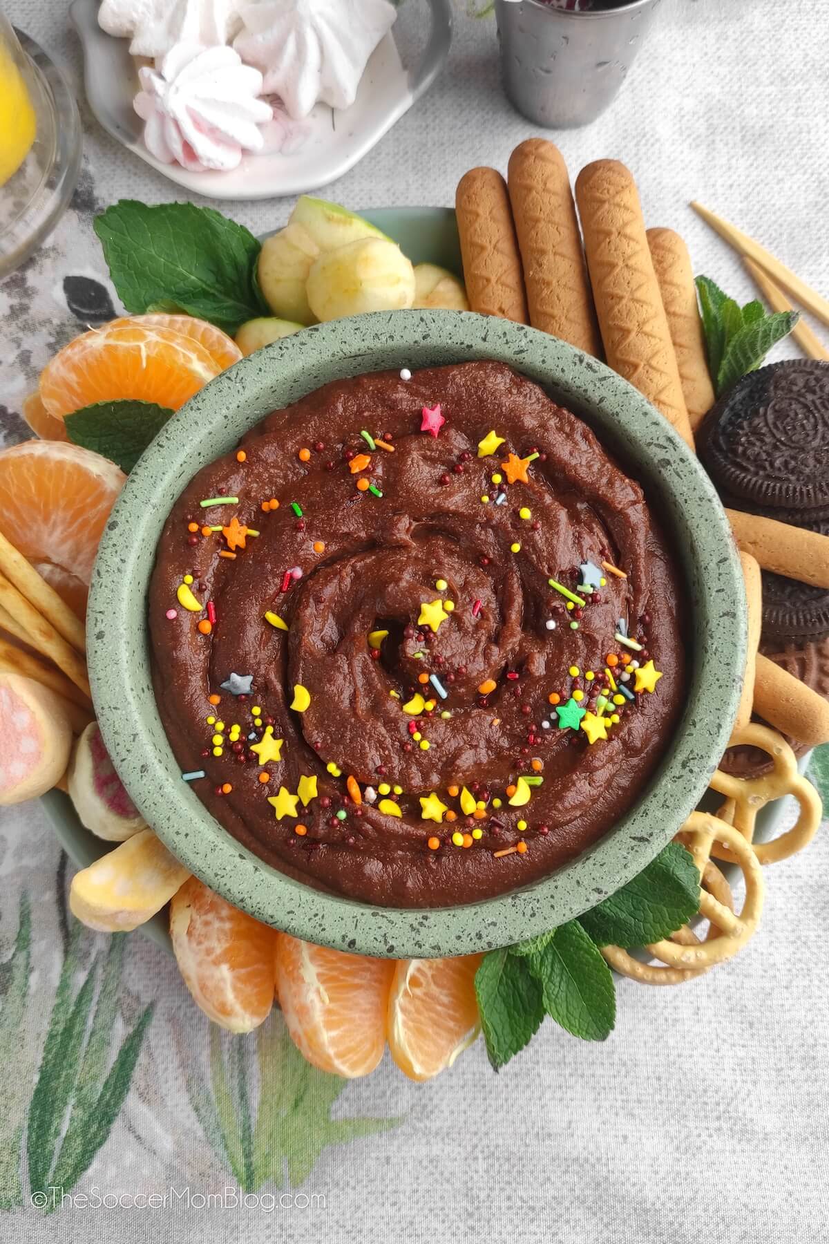 bowl of chocolate hummus dip, with fruit and pretzels 