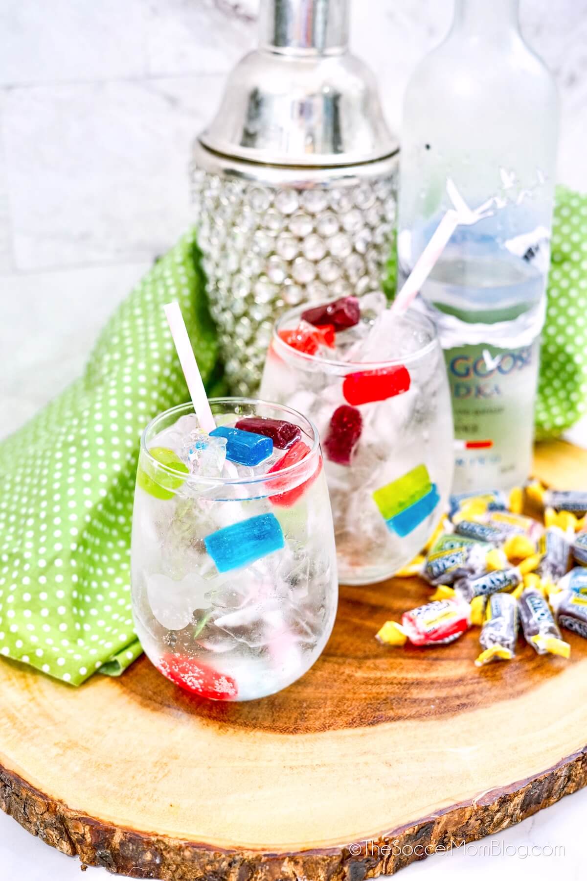 two Jolly Rancher cocktails, with cocktail shaker, candy, and vodka bottle