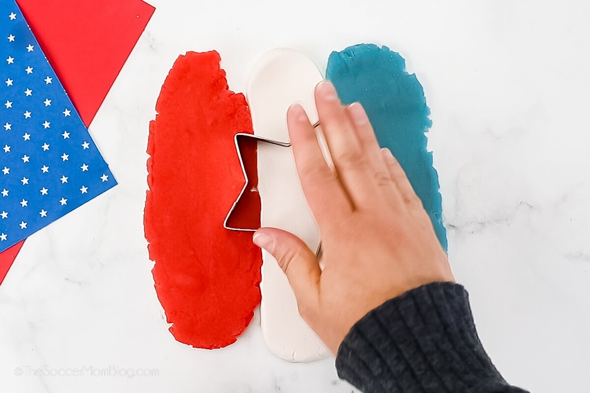 using a star cookie cutter on red, white, and blue playdough