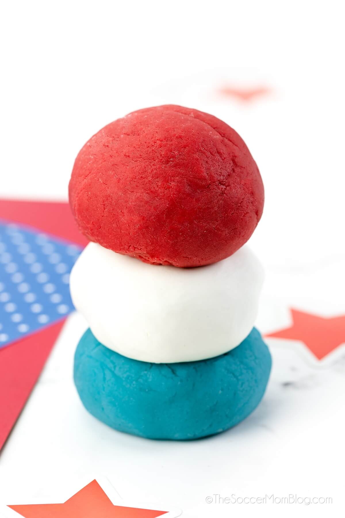 three balls of playdough stacked: red, white, and blue colors