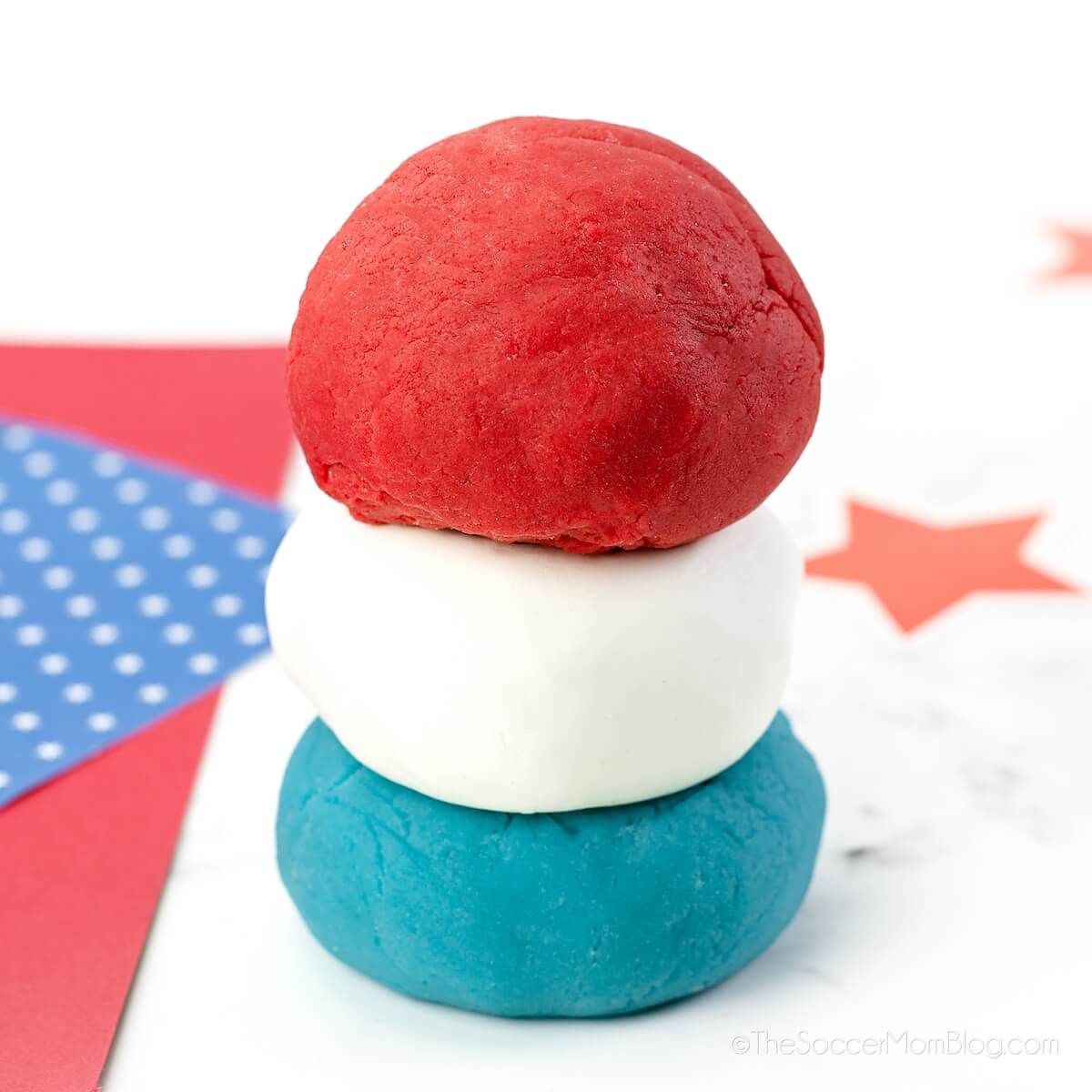 three balls of playdough stacked: red, white, and blue colors