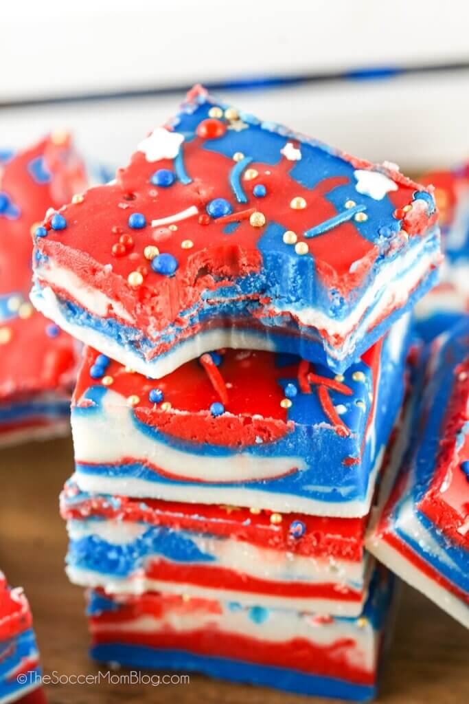 stack of red white and blue swirled fudge squares, top piece has a bite taken