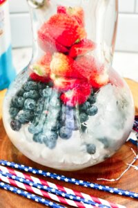 close up of a pitcher filled with ice cubes and fresh blueberries, strawberries, and raspberries