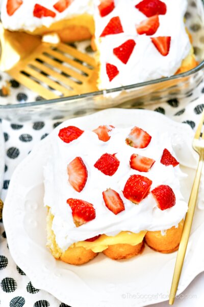 close up on a slice of Strawberry Twinkie Cake, with a layer of Twinkies, pudding, whipped topping, and strawberries