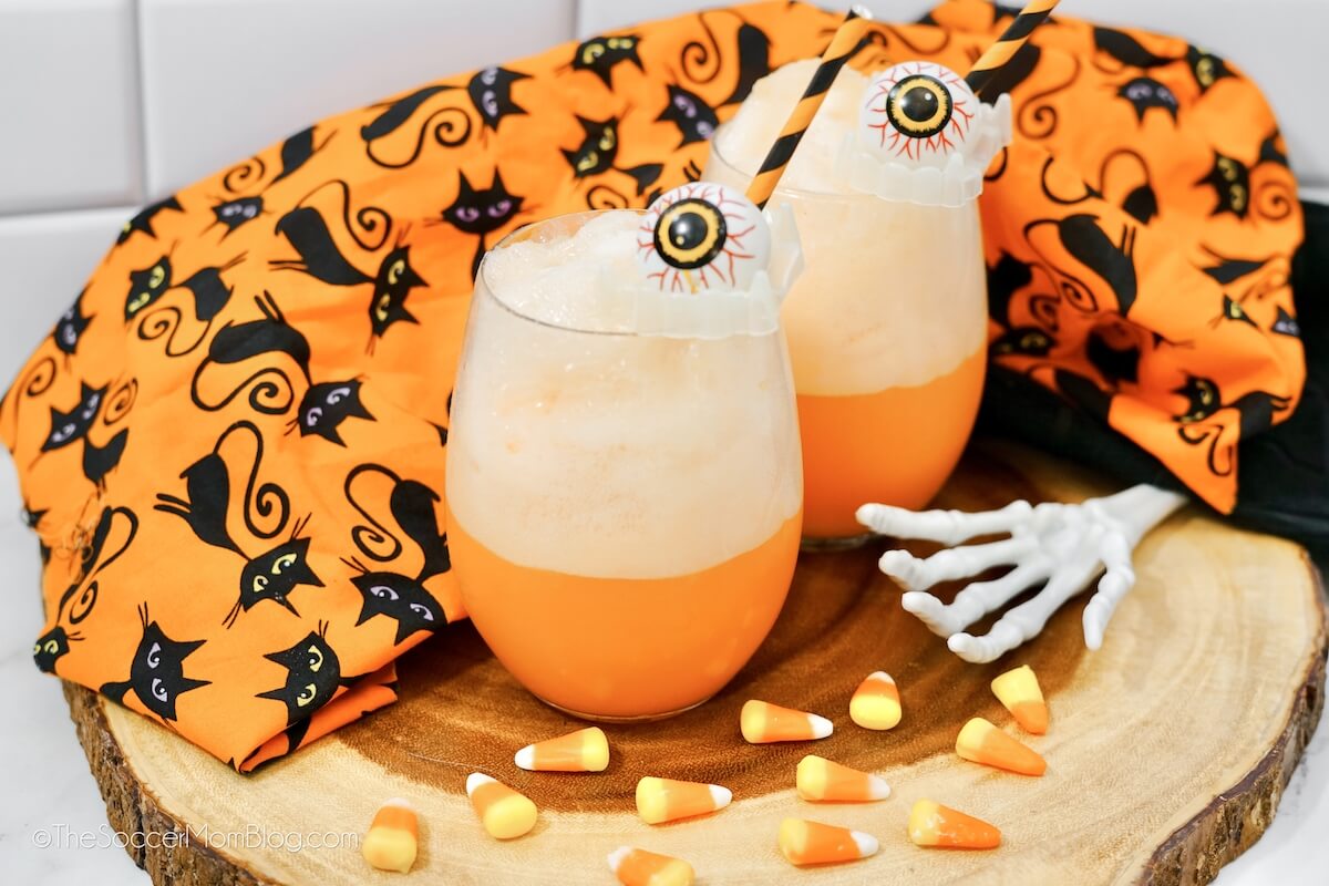 orange Halloween ice cream Floats on a wooden platter, with candy corn and Halloween decor