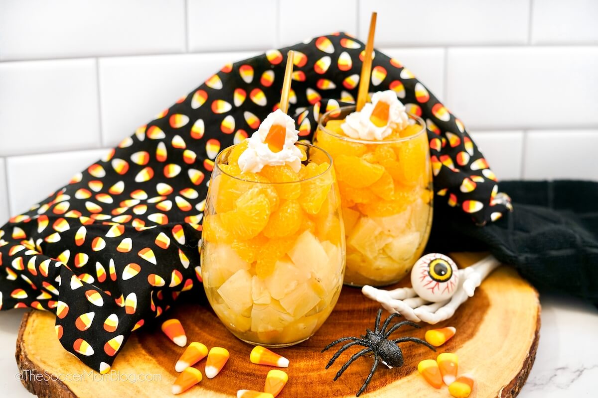 Halloween Fruit Parfaits on a wooden board surrounded by Halloween decor