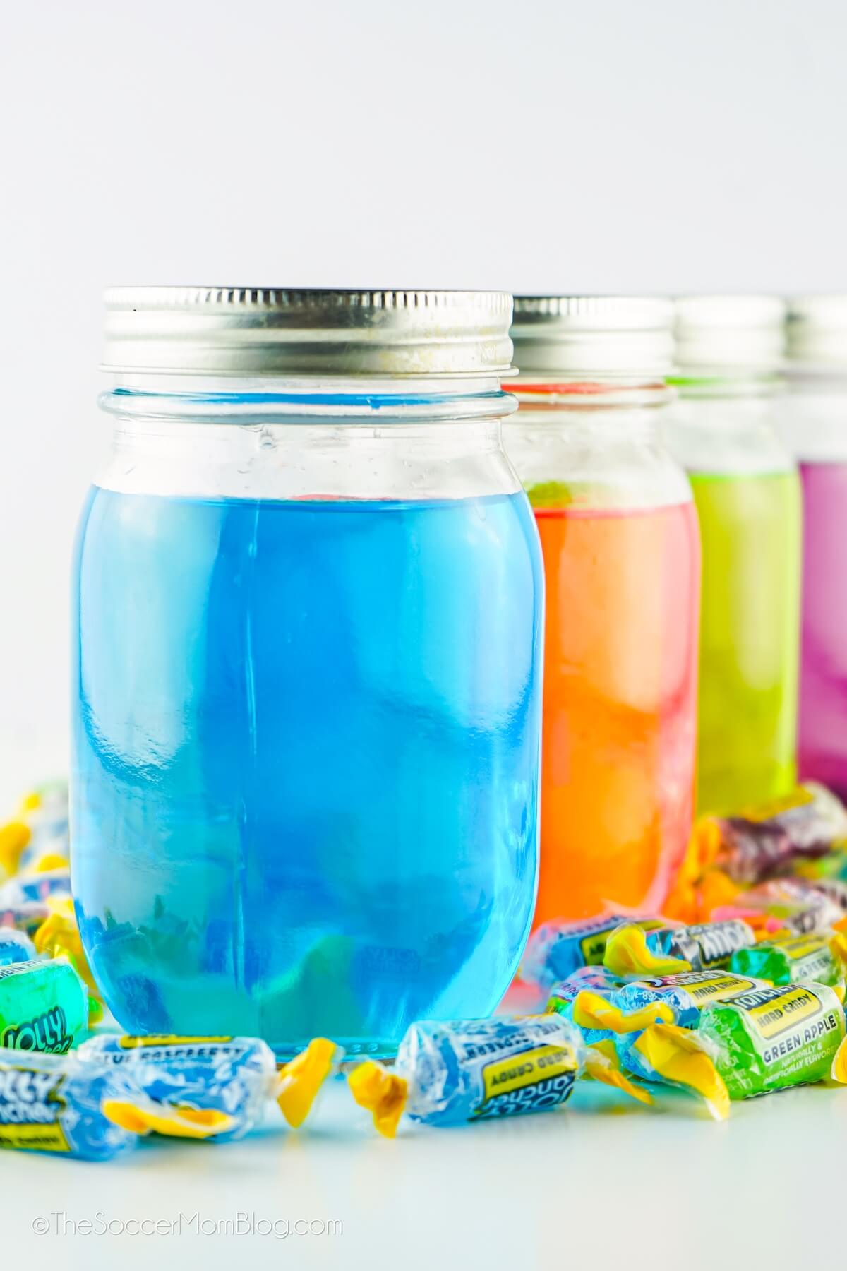 4 mason jars filled with different colors of Jolly Rancher Moonshine