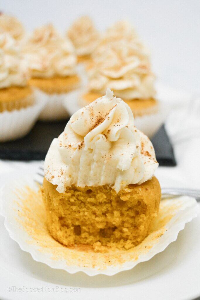 close up of a frosted pumpkin cupcake, with bite missing