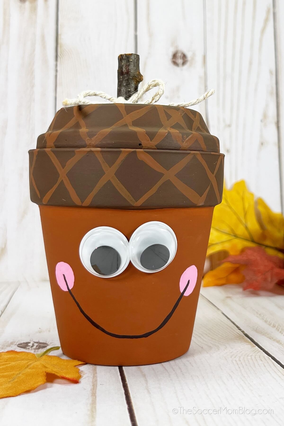 terra cotta pot painted to look like an acorn, with a smiley face