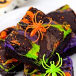 stack of colorful Halloween brownies with orange, green, and purple cheesecake swirl.