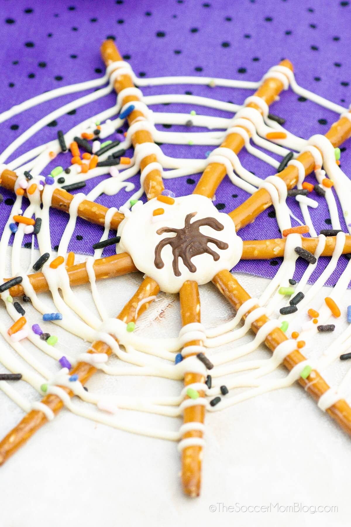 close up of a spiderweb treat made with pretzel sticks and white chocolate drizzle