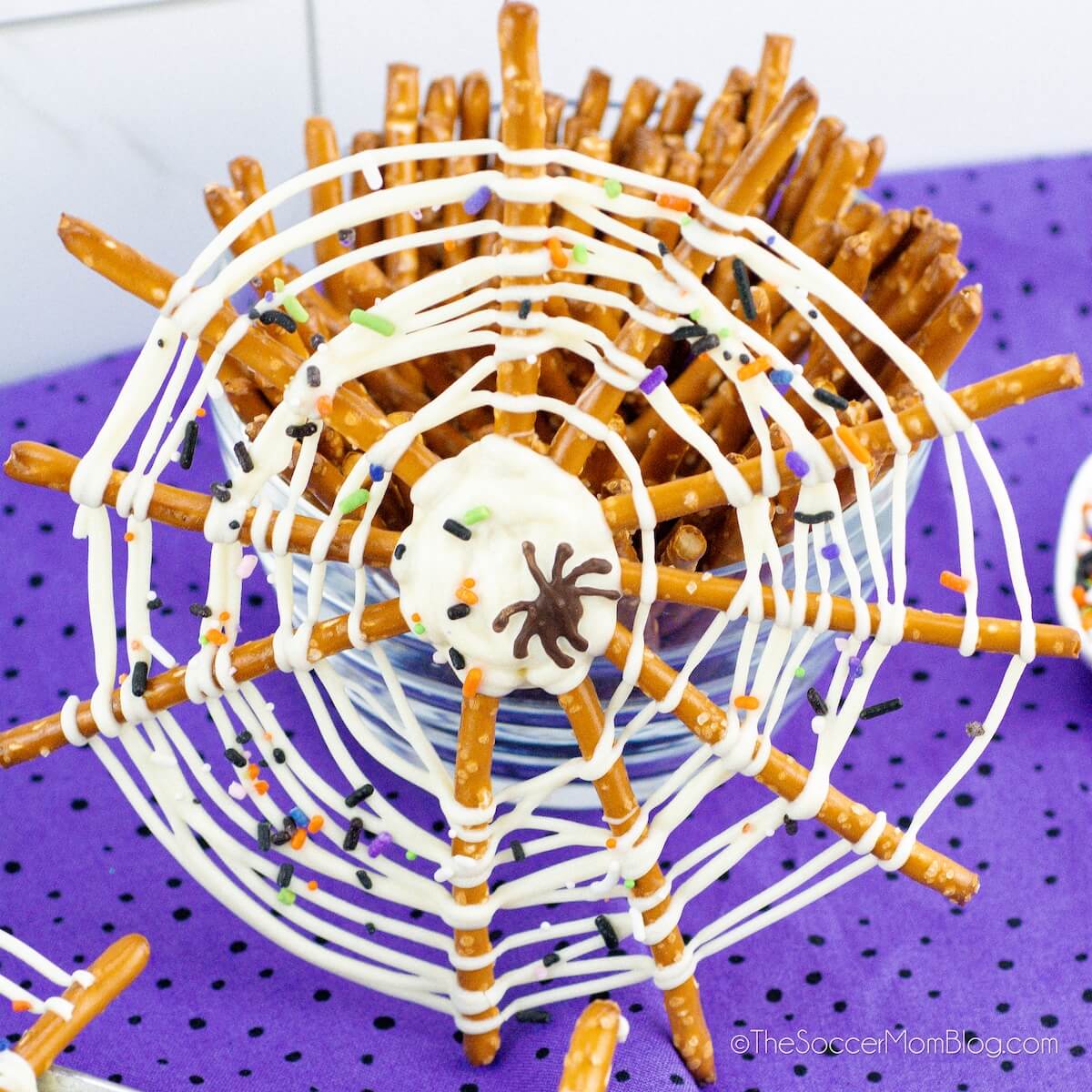 a spiderweb made with pretzel sticks and white chocolate drizzle