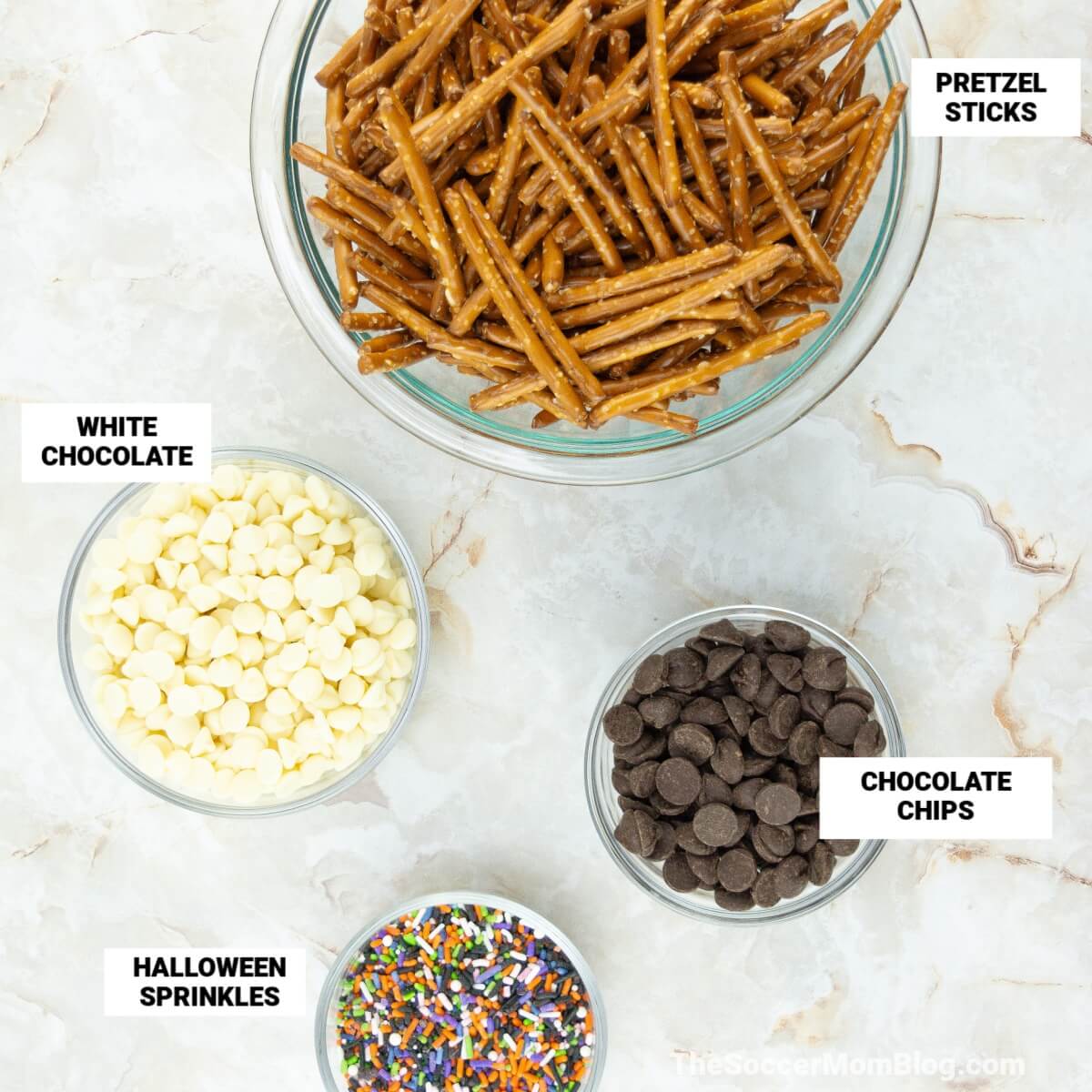 photo of ingredients to make pretzel spiderwebs: pretzel sticks, white chocolate, chocolate chips, and Halloween sprinkles