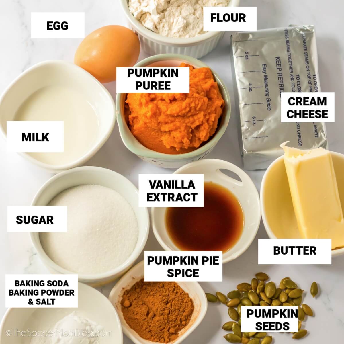 ingredients to make Starbucks pumpkin muffins, with text labels: egg, flour, pumpkin, milk, cream cheese, vanilla, sugar, butter, baking soda, baking powder, salt, pumpkin spice, pumpkin seeds