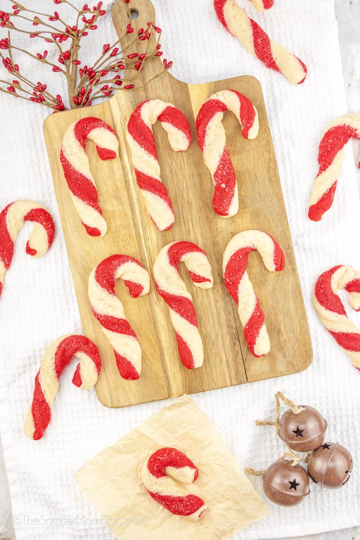 candy cane shaped sugar cookies on a wooden serving board.