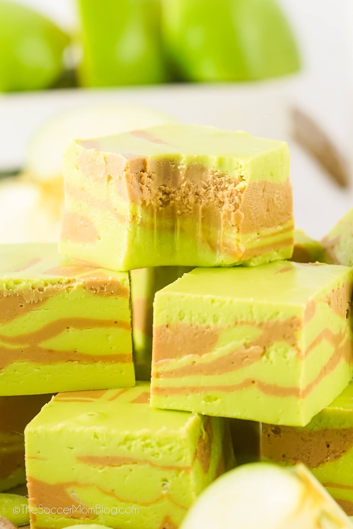 close up of green and brown caramel apple swirled fudge. The top square has a bite missing.