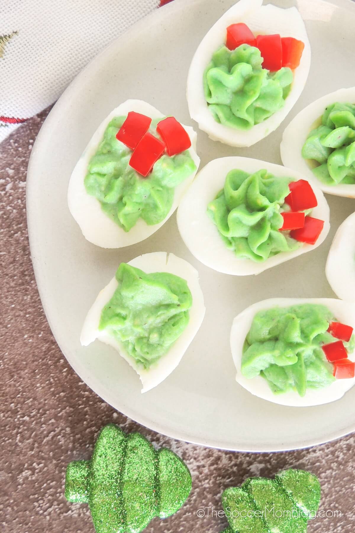 Christmas Deviled Eggs on a white plate, one with a bite taken.