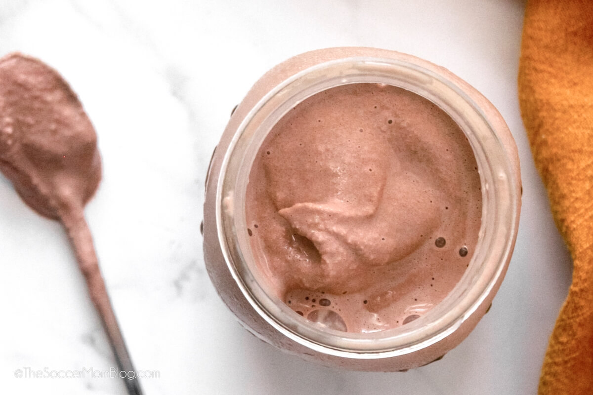 top down view of a chocolate frosty in a mason jar, with spoon on counter