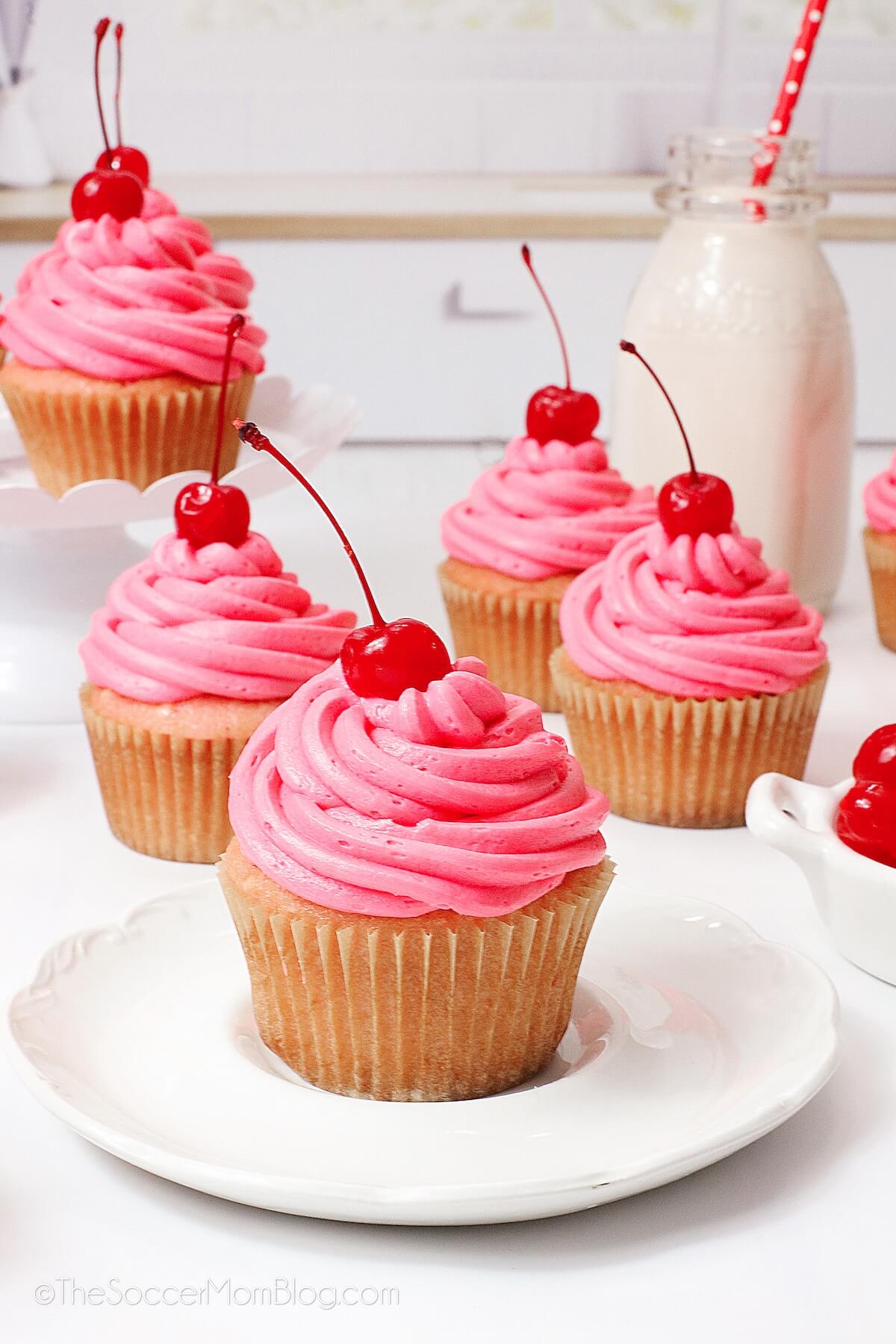 Cherry Cupcakes on plate, jar of milk in background.