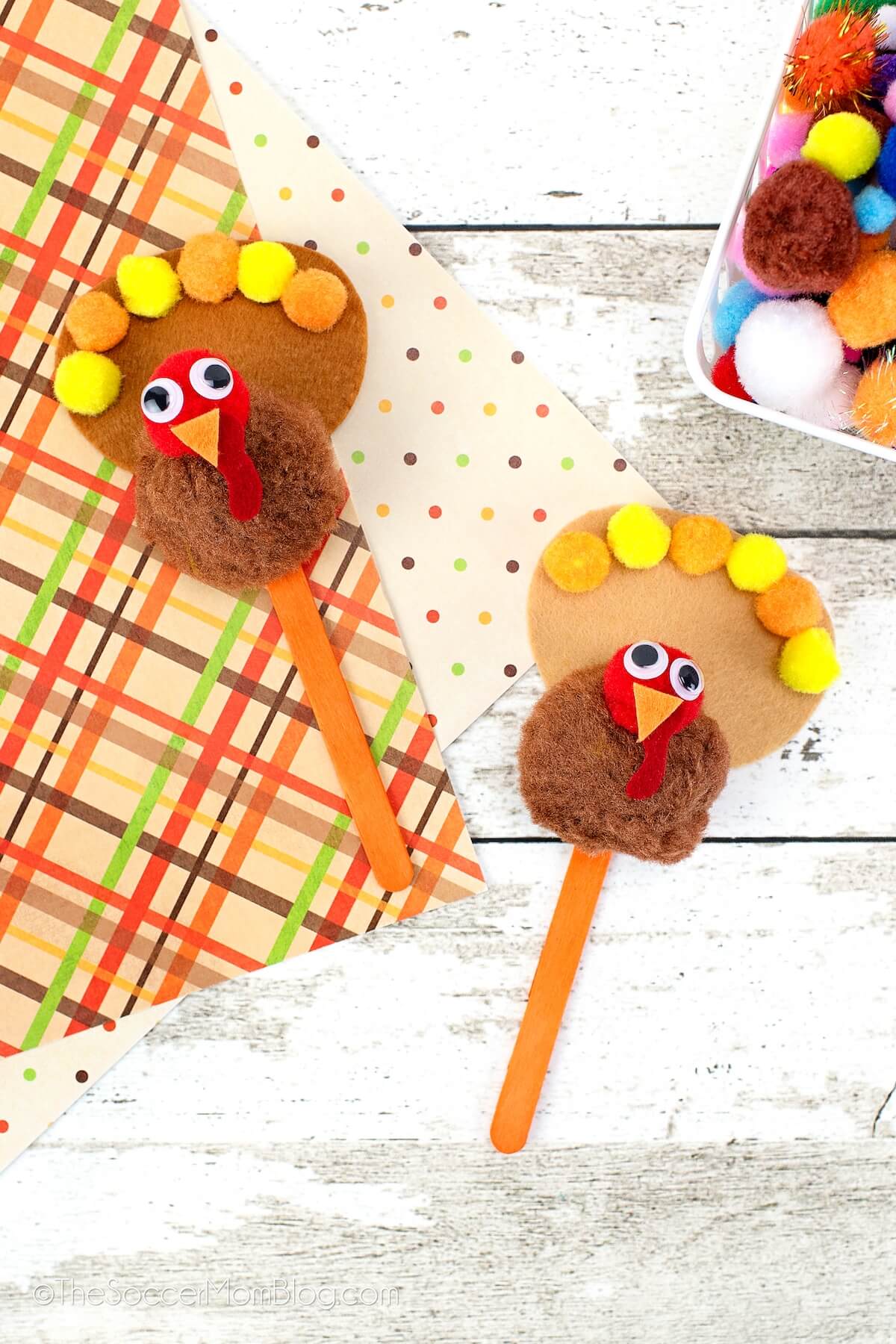 2 turkey puppets made with pom poms and popsicle sticks.
