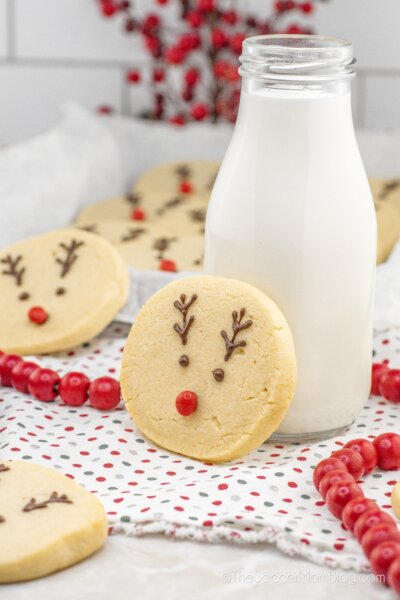 sugar cookie decorated with a reindeer face, propped up on a bottle of milk.