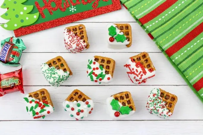 white chocolate dipped pretzel squares with holiday sprinkles.