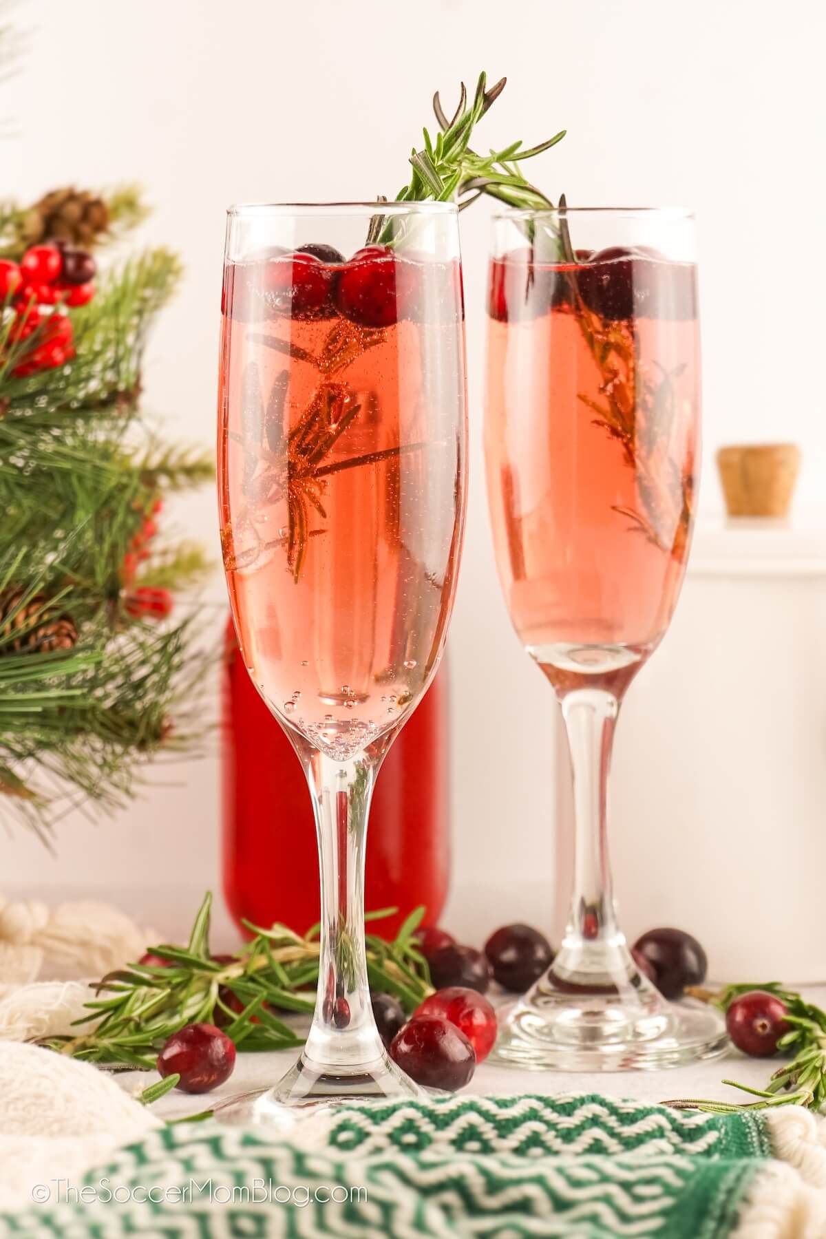 2 pink colored Christmas mimosas in champagne flutes.