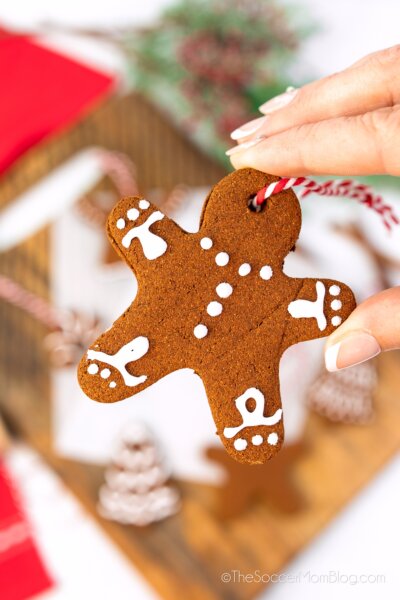 hand holding a homemade cinnamon ornament shaped like a gingerbread man.