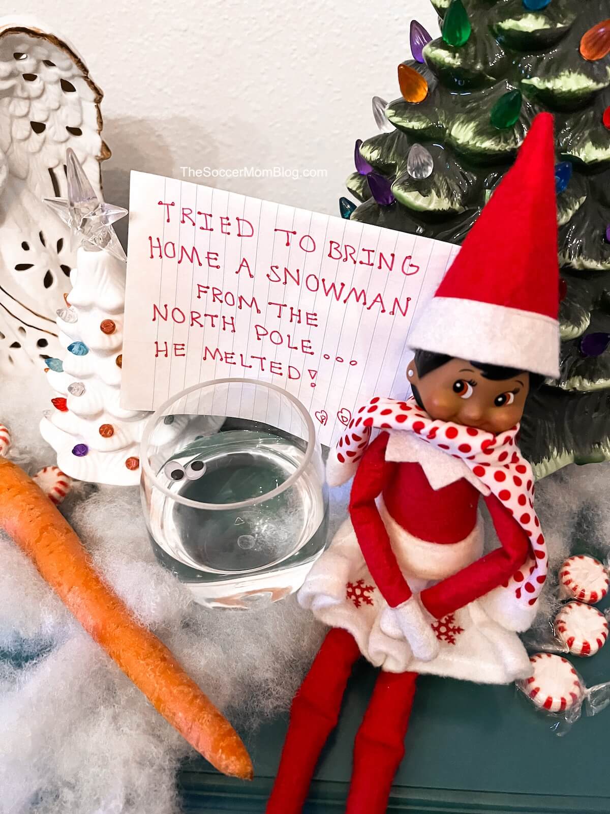 Elf on the Shelf with a "melted snowman" in a glass.