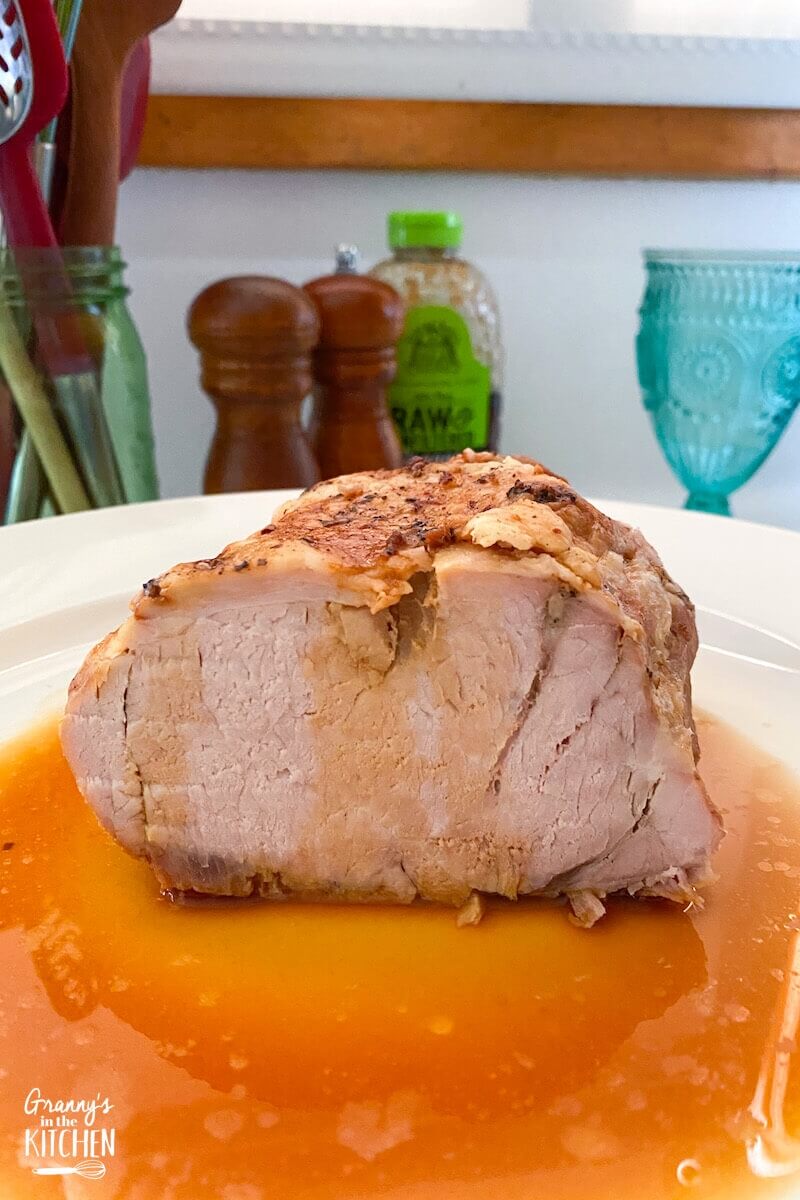 half of a pork loin roast in a plate of juices.