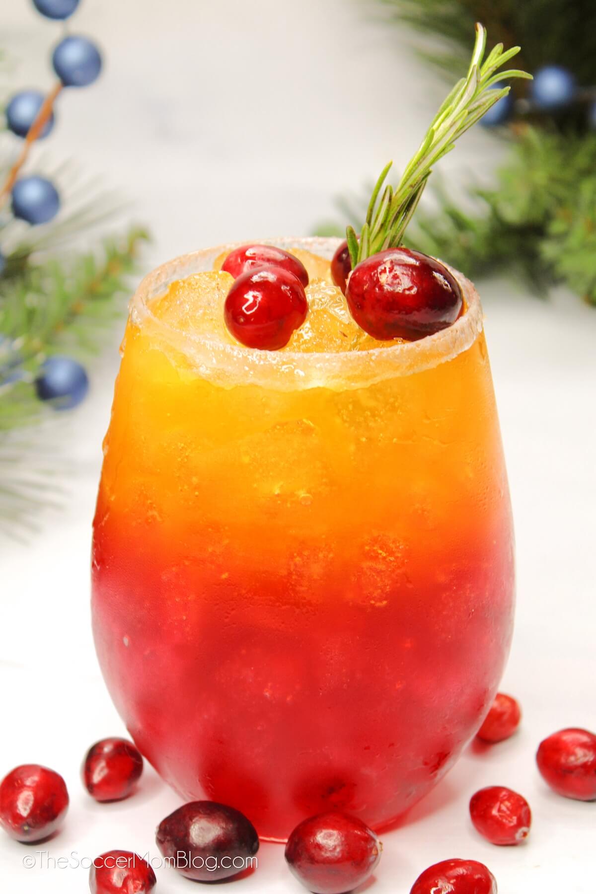 close up of a red and gold layered holiday drink, topped with cranberries.