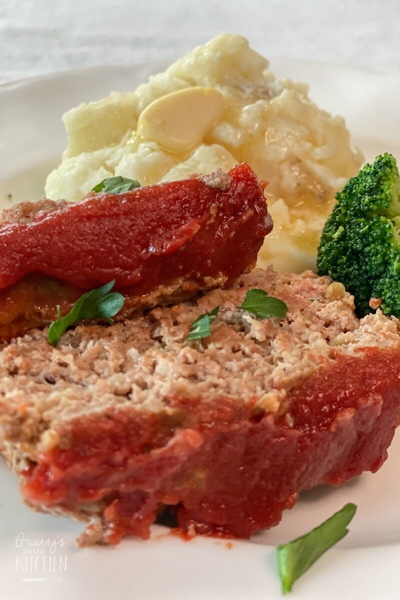 two slices of meatloaf, with broccoli and mashed potatoes.