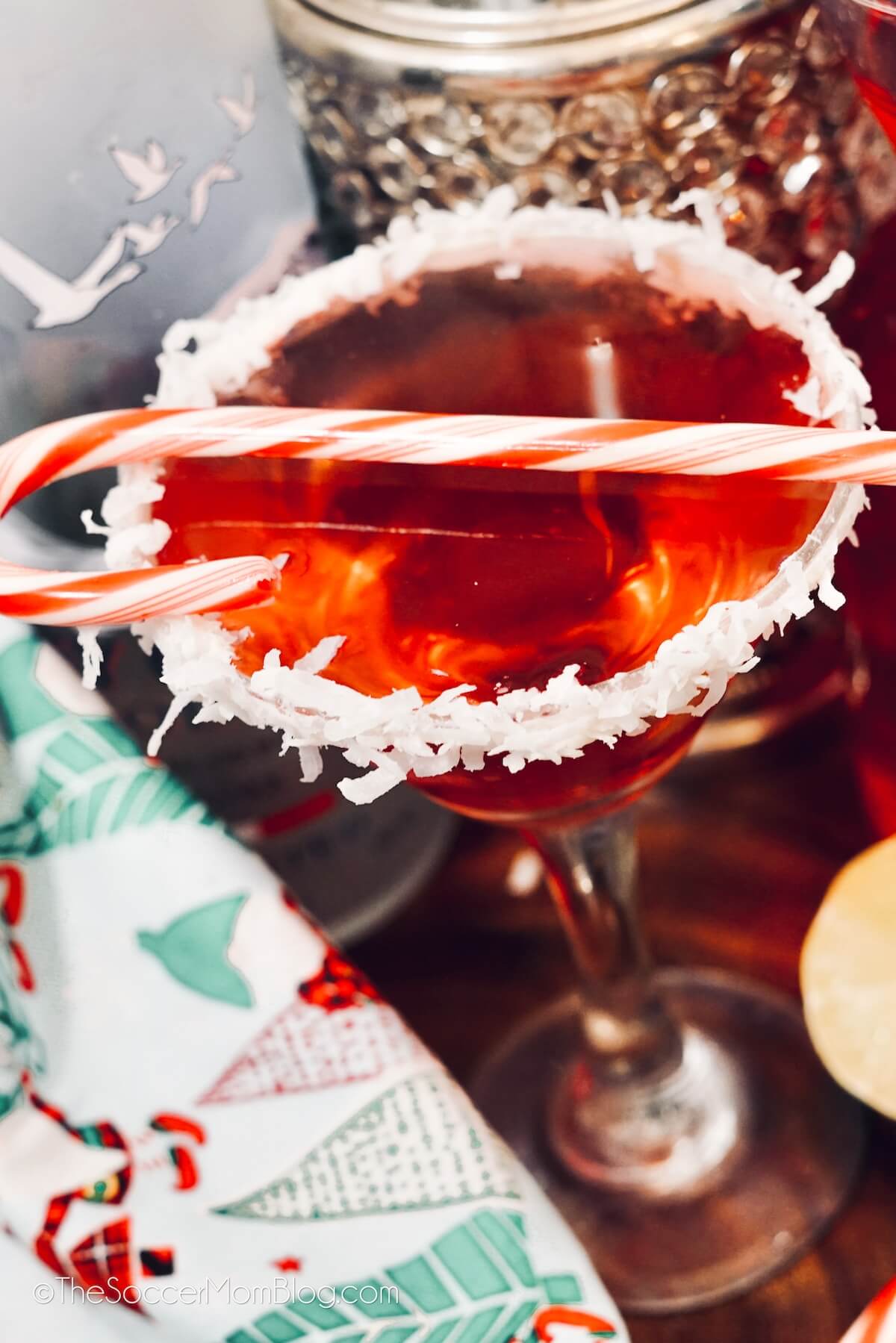 close up of a bright red "Santa Clausmopoltan" cocktail, garnished with a candy cane.