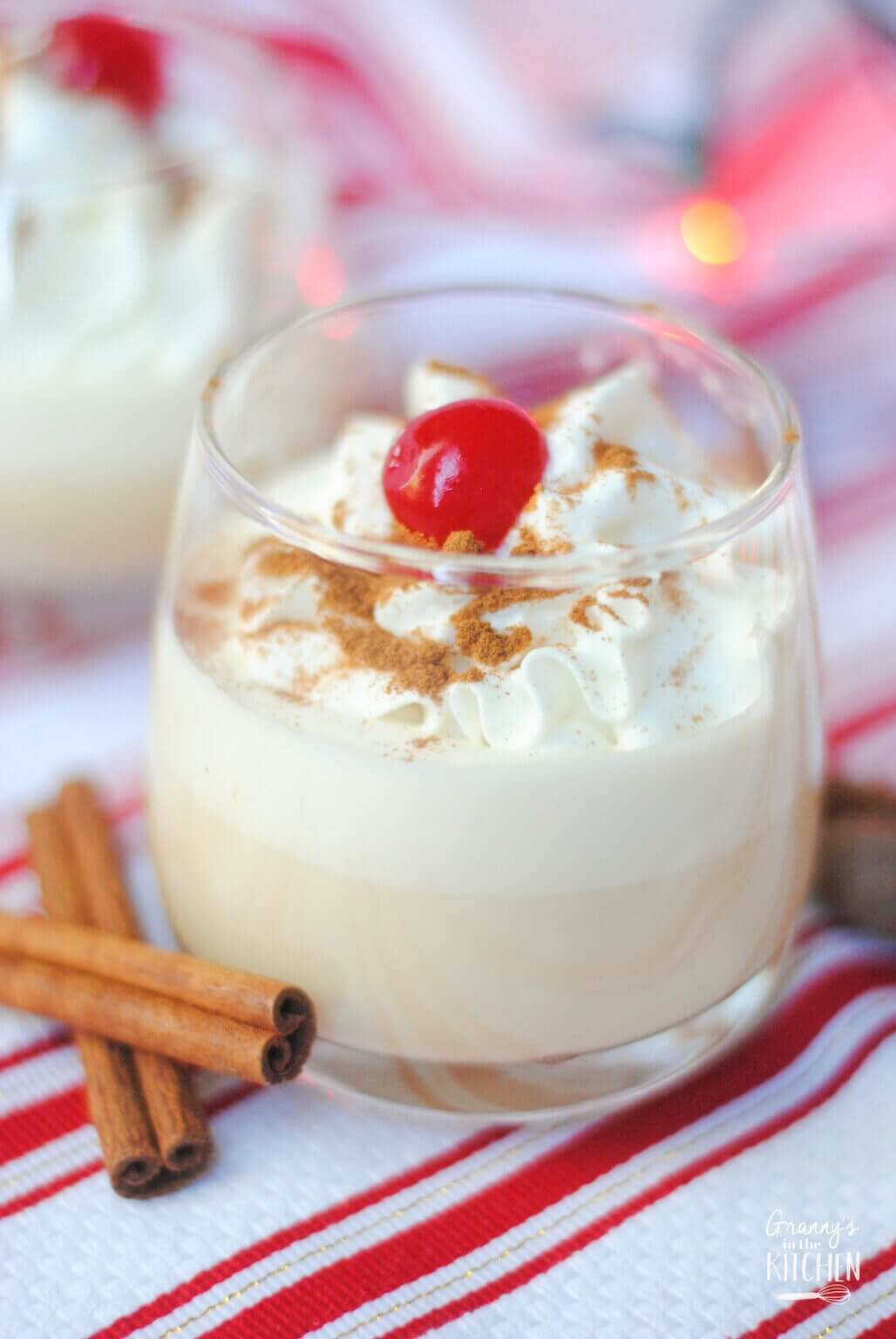 a glass of eggnog topped with whipped cream.