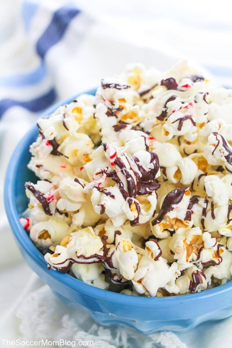a bowl of popcorn with chocolate drizzle and peppermint pieces.
