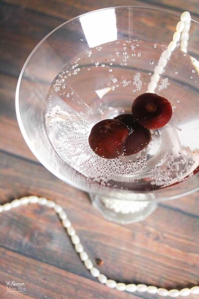 clear sparkling martini with black cherries.