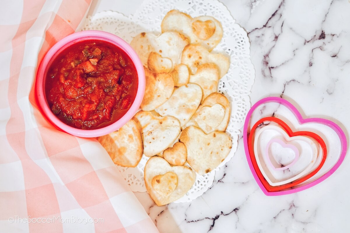 heart shaped tortilla chips with bowl of salsa and heart cookie cutters.